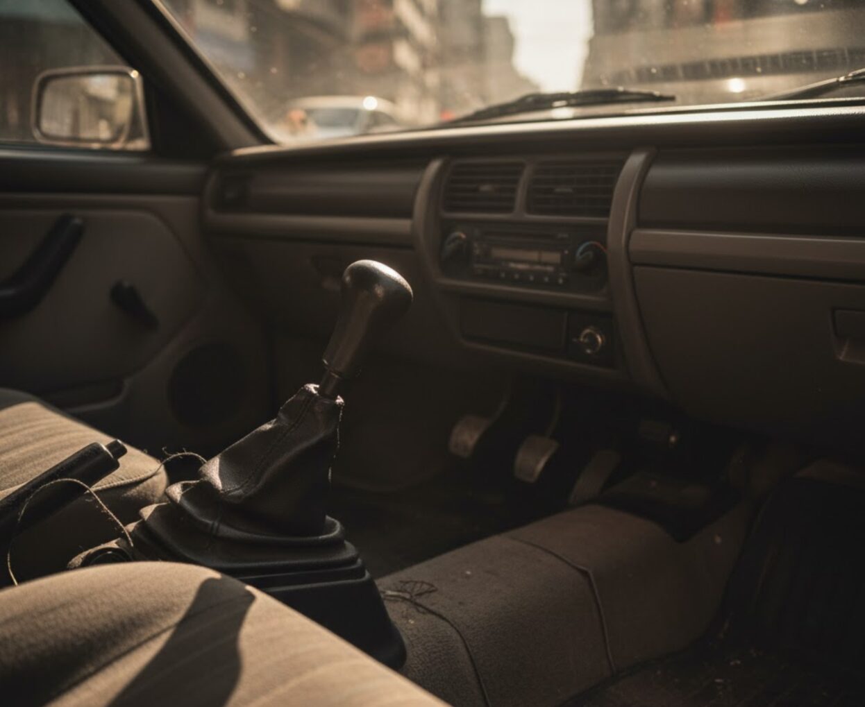 マニュアル（MT）車のシフトレバーとクラッチペダルを写した車内のクローズアップ。カーシェアでの故障リスクとメンテナンスコストを象徴する画像。