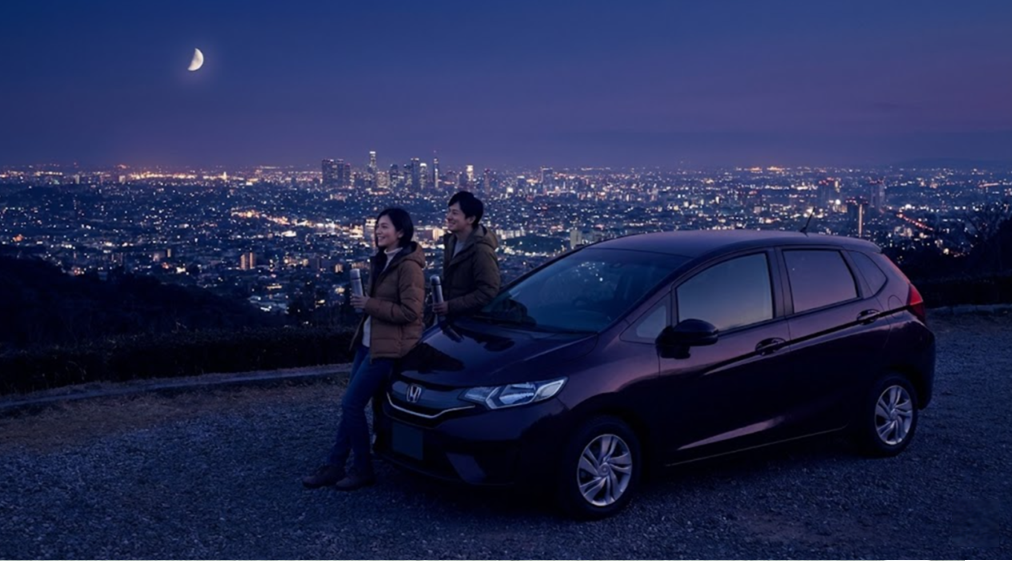 夜間パックを利用し、街の夜景が見える静かな高台で休憩している日本のカップル。